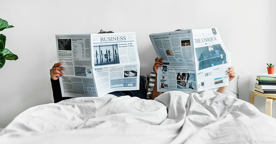 Pärchen liest Zeitung im Bett